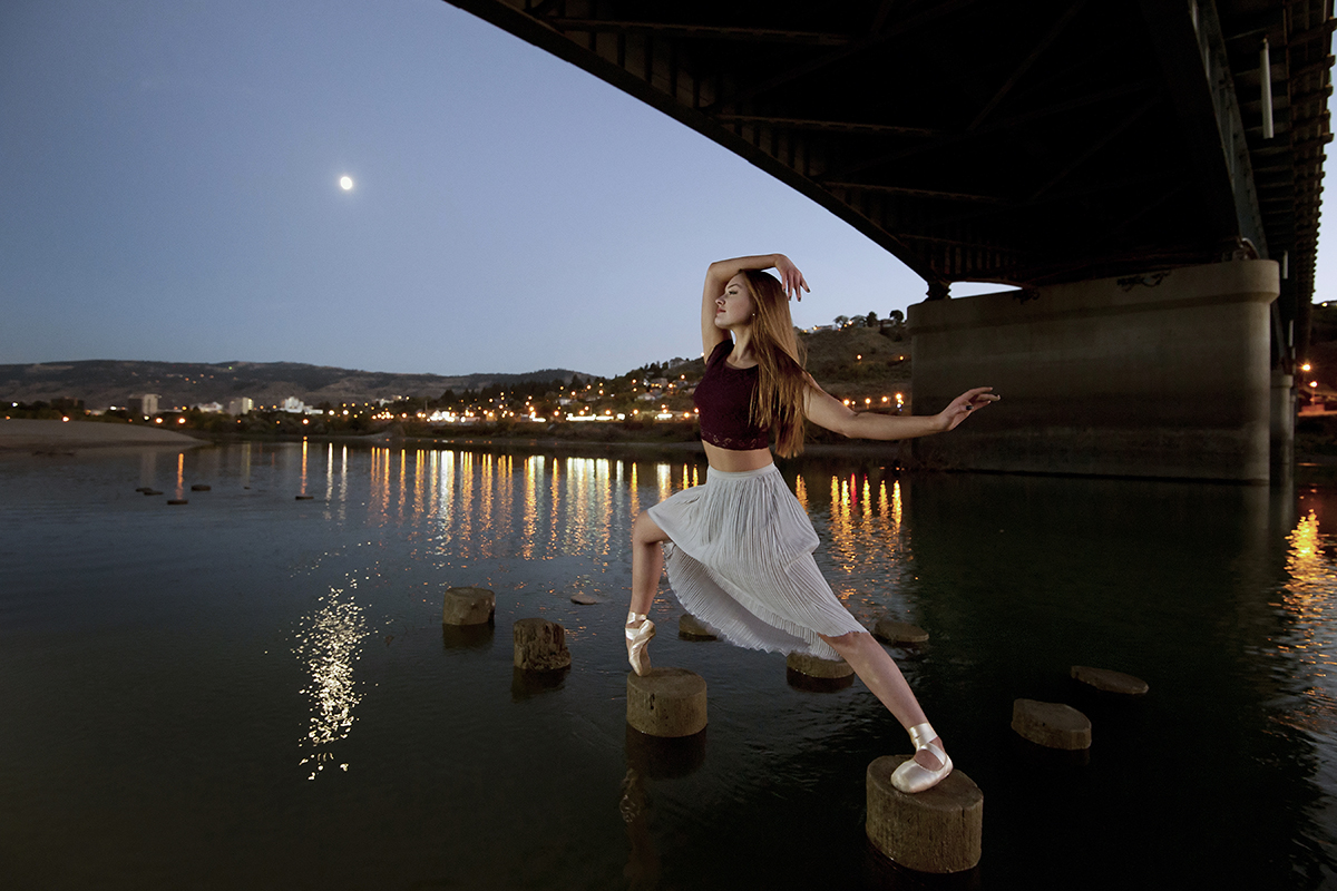 A beautiful, young ballet dancer poses under the Overlander bridge, on the Thompson river, Kamloops, Thompson Okangan region, British Columbia, Canada