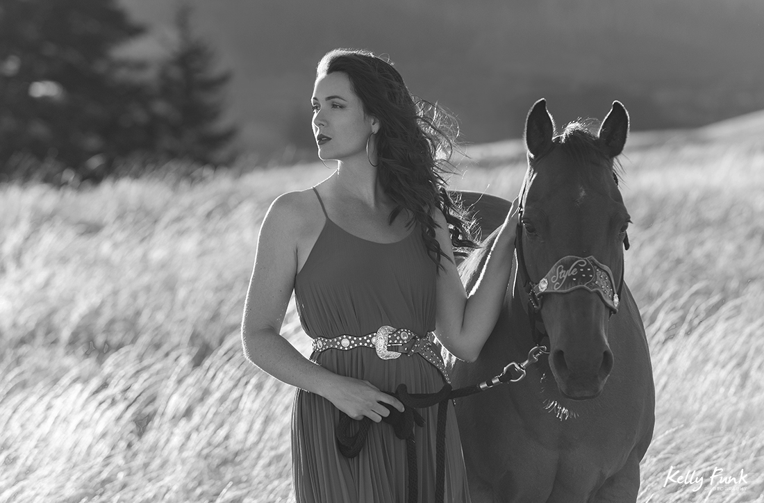 A beautiful woman and her horses walk the fields at sunset for a portrait during sunset on the ranch near Kamloops, British Columbia, Canada