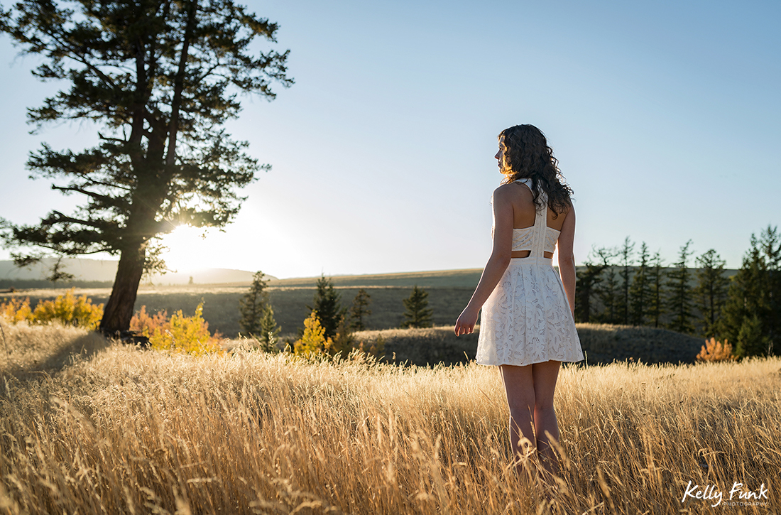 A young woman enjoys a gorgeous sunset in the grasslands of British Columbia, Canada during a commercial photo shoot