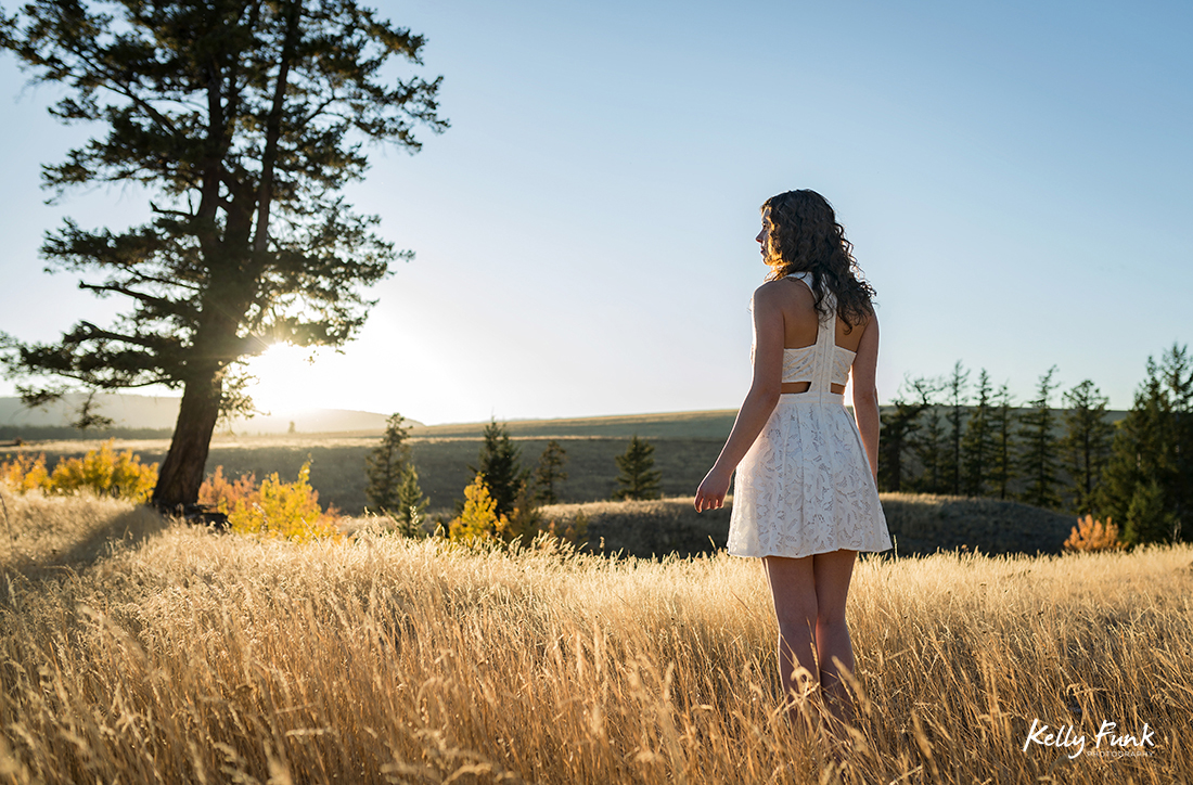 A beautiful young woman enjoys a gorgeous sunset in the grasslands of British Columbia, Canada during a commercial photo shoot
