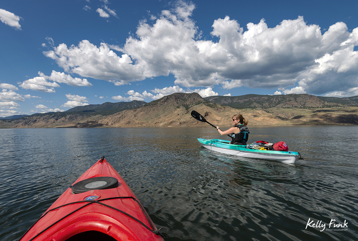 Kayakers travel west on Kamloops Lake for an assignment, Thompson Okanagan region of British Columbia, Canada