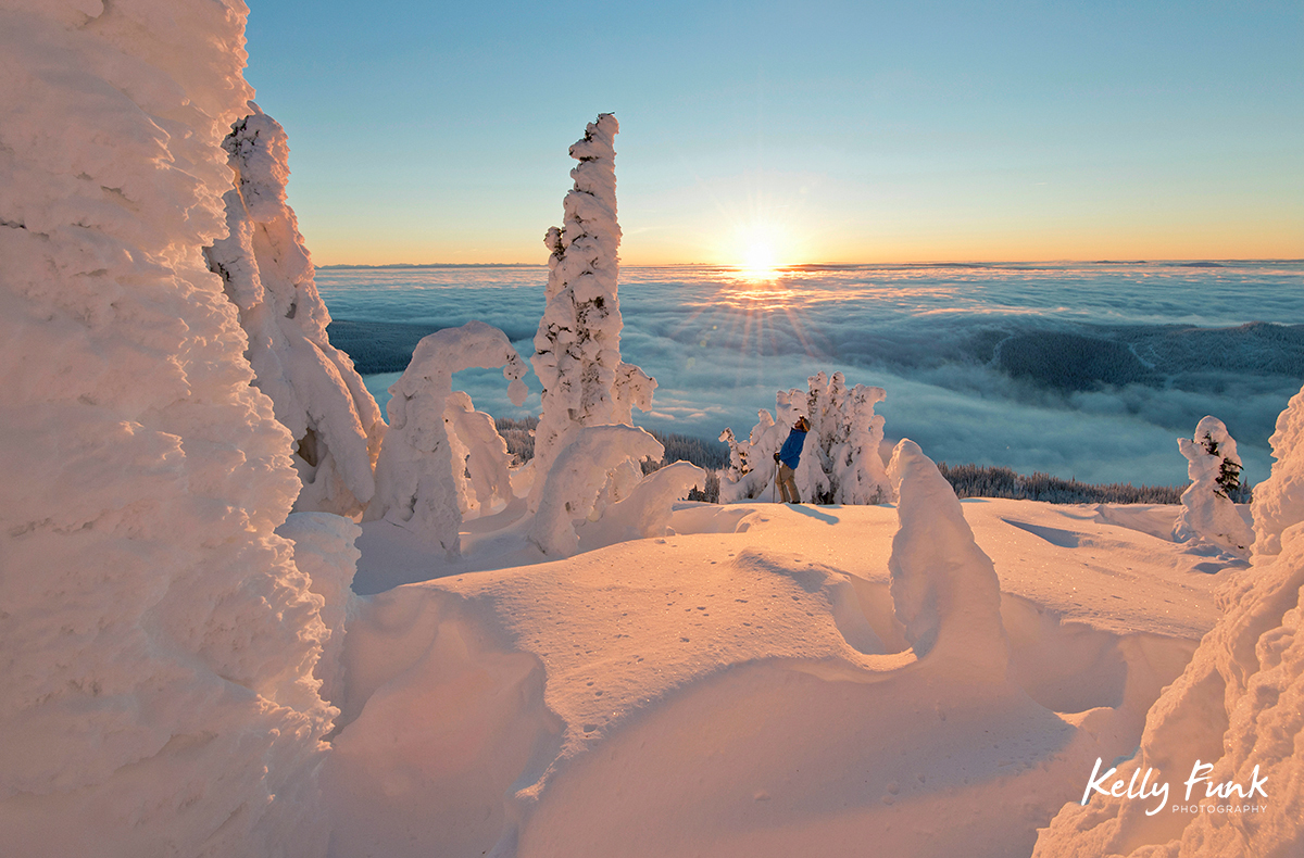 A skier rests among the snow ghosts while surveying the beautiful landscape at sunrise at the top of Sun Peaks Resort, Thompson Okangan region, British Columbia, Canada