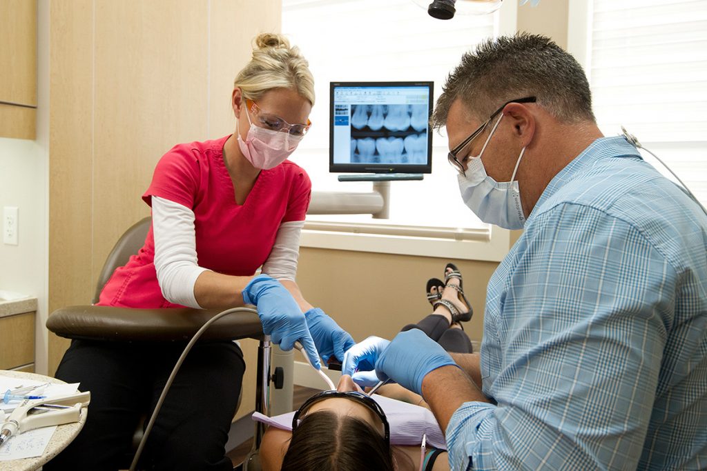 A dentist and assistant work on a patient at Carrington Dental in Kelowna, British Columbia during a commercial photography shoot, Canada